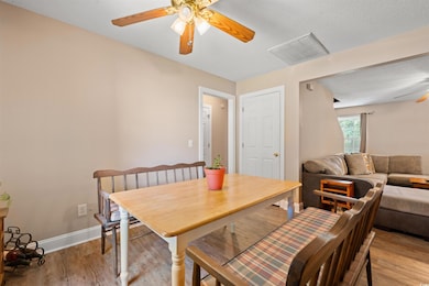 Dining room with ceiling fan, light wood-style flooring, and a textured ceiling