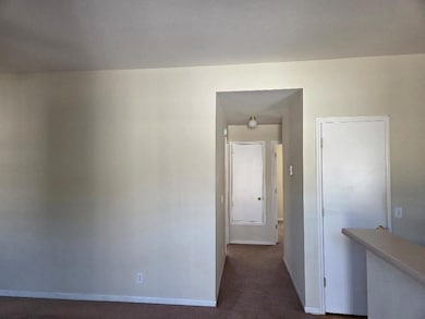 Hallway with baseboards and dark carpet