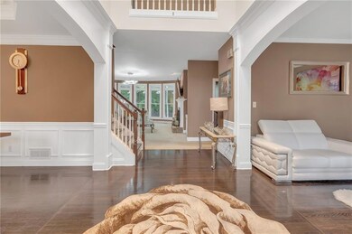 Foyer with arched walkways, wood finished floors, stairway, and crown molding