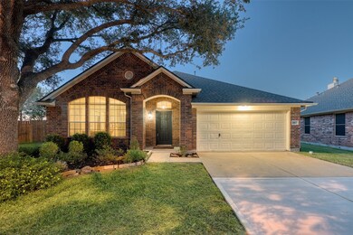 Charming front elevation with fresh exterior paint (Oct 2025), mature oak tree, covered entry, and warm brick façade welcoming you home.