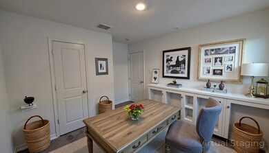Office area with dark colored carpet and baseboards