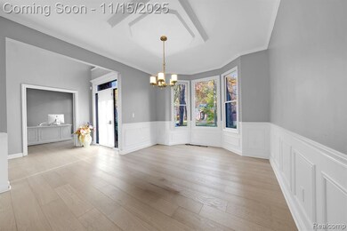 Unfurnished dining area with a chandelier, wood finished floors, ornamental molding, and wainscoting