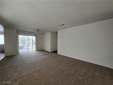 Carpeted spare room featuring a textured ceiling and a ceiling fan