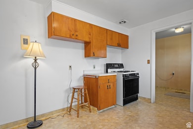Kitchen with gas stove, visible vents, light floors, light countertops, and brown cabinets