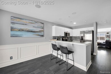 Kitchen featuring white cabinets, a breakfast bar area, light countertops, a peninsula, and appliances with stainless steel finishes