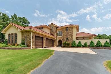 Mediterranean / spanish home featuring stone siding, a garage, asphalt driveway, and a front lawn