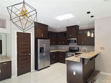 Kitchen featuring stainless steel refrigerator with ice dispenser, hanging light fixtures, decorative backsplash, light tile patterned floors, and dark brown cabinetry