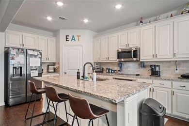 Kitchen featuring white cabinetry, dark hardwood / wood-style flooring, decorative backsplash, a center island with sink, and appliances with stainless steel finishes