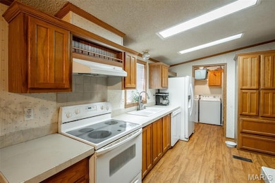 Kitchen featuring white appliances, lofted ceiling, light wood-type flooring, under cabinet range hood, and light countertops