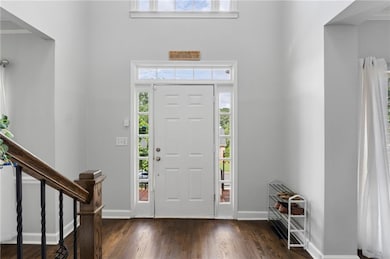 Entrance foyer featuring plenty of natural light, dark wood-style floors, and a towering ceiling
