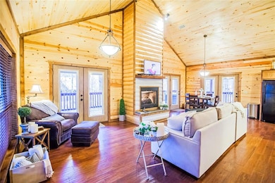 Living area with french doors, high vaulted ceiling, hardwood / wood-style floors, wood ceiling, and wood walls