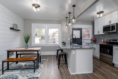 Kitchen featuring pendant lighting, a center island with sink, dark hardwood floors, stainless steel appliances, and white cabinetry