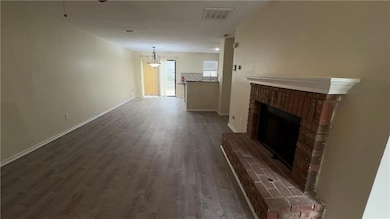 Unfurnished living room with a fireplace, dark wood finished floors, a textured ceiling, and a ceiling fan