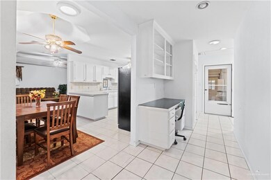 Kitchen with black refrigerator, light tile patterned flooring, white cabinetry, and tasteful backsplash