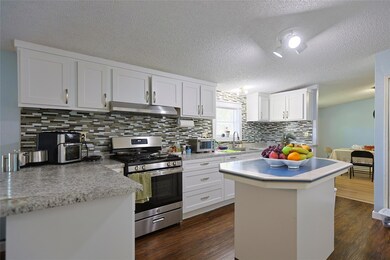 Kitchen with a center island, stainless steel range with gas stovetop, tasteful backsplash, white cabinets, and a textured ceiling