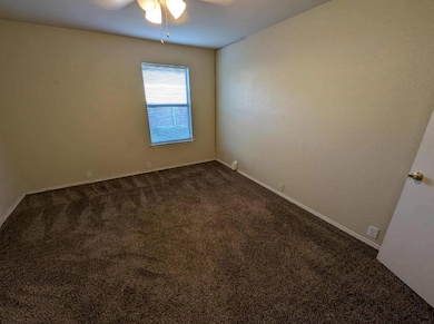 Spare room with dark carpet and baseboards