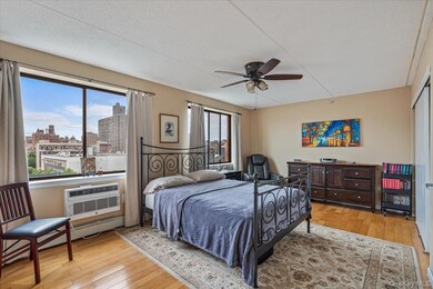 Bedroom featuring hardwood / wood-style floors, a textured ceiling, a view of city, a wall mounted air conditioner, and ceiling fan
