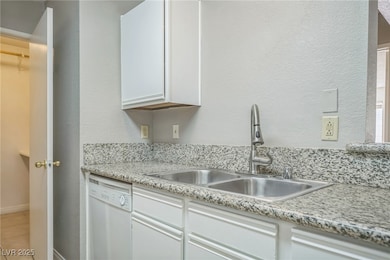 Kitchen with white dishwasher, a sink, light tile