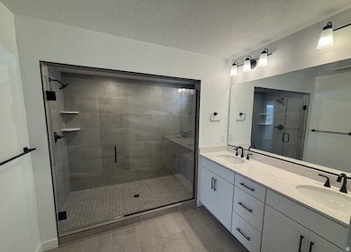Bathroom with double vanity, a stall shower, and a textured ceiling