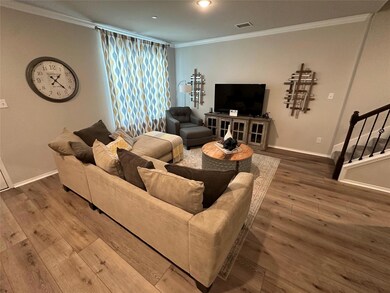 Living room with wood-type flooring and crown molding