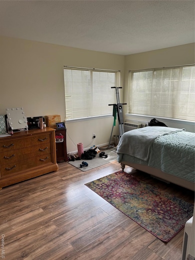 Bedroom with a textured ceiling and wood finished floors