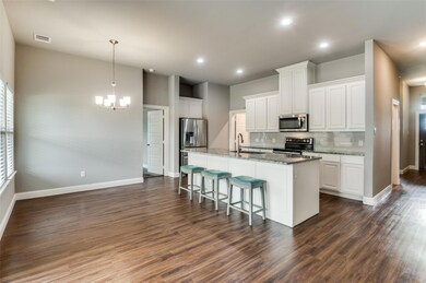 Kitchen featuring pendant lighting, stainless steel appliances, dark hardwood / wood-style flooring, and white cabinetry