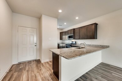 Kitchen with dark brown cabinets, light stone countertops, a peninsula, stainless steel appliances, and recessed lighting