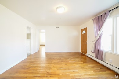 Unfurnished room with a baseboard radiator and light wood finished floors
