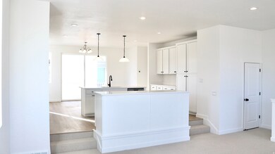 Kitchen featuring white cabinets, a center island with sink, pendant lighting, light colored carpet, and recessed lighting