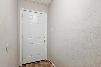 Doorway to outside featuring dark tile flooring and a textured ceiling