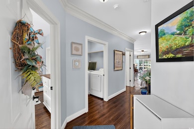 Corridor with crown molding, dark wood-style flooring, and washer and dryer