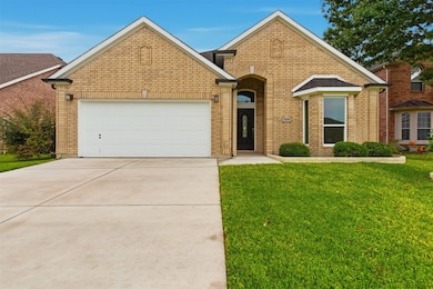 Traditional-style house featuring a front yard, driveway, brick, and a 2-car garage