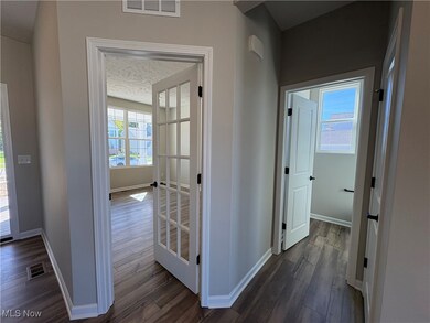 Hall featuring dark wood-type flooring, healthy amount of natural light, and a textured ceiling