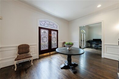 Foyer entrance with ornamental molding, wood finished floors, french doors, and wainscoting