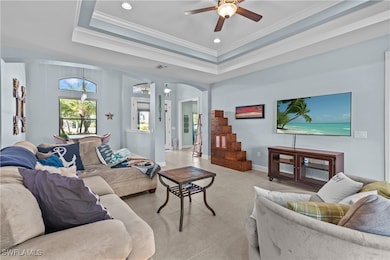 Living room with arched walkways, ceiling fan, crown molding, light tile patterned floors, and recessed lighting