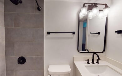 Bathroom with toilet, vanity, and tiled shower