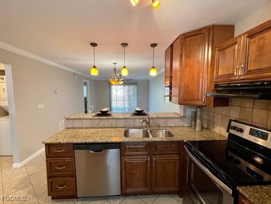 Kitchen with a peninsula, appliances with stainless steel finishes, decorative backsplash, decorative light fixtures, and under cabinet range hood