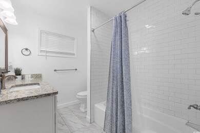 Full bath with shower / bath combo with shower curtain, vanity, and light marble finish flooring