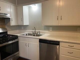 Kitchen with appliances with stainless steel finishes, sink, and white cabinets
