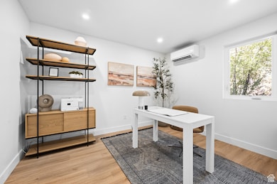 Bright Office Space featuring Light Wood Finished Floors, Recessed Lighting, and a Wall Unit AC