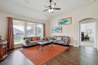 Living room with vaulted ceiling, hand-scraped hardwood style flooring, ceiling fan, and a wealth of natural light