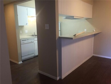 Kitchen featuring white dishwasher, white cabinets, dark wood-type flooring, and light countertops