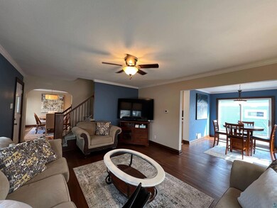Living area with arched walkways, dark wood-style flooring, and crown molding