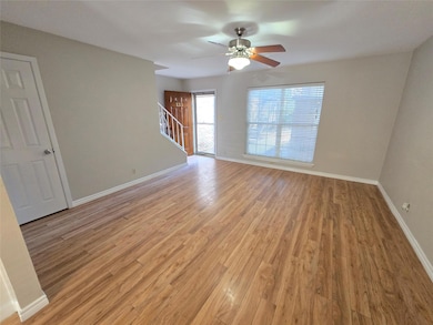 Empty room with light wood-type flooring, stairway, and a ceiling fan
