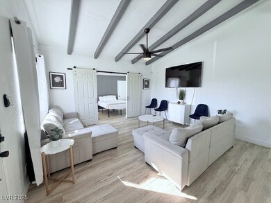Living area with light wood-style floors, a ceiling fan, and a barn door