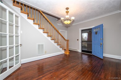 The large foyer has stunning wood floors, a chande