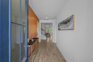 Hall with light wood-style floors, stairway, and baseboards