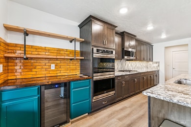 Kitchen with beverage cooler, open shelves, appliances with stainless steel finishes, decorative backsplash, and a textured ceiling