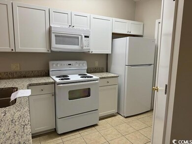 Kitchen with white cabinets, light stone counterto