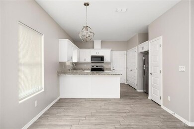 Kitchen with appliances with stainless steel finishes, a chandelier, a peninsula, and light wood finished floors